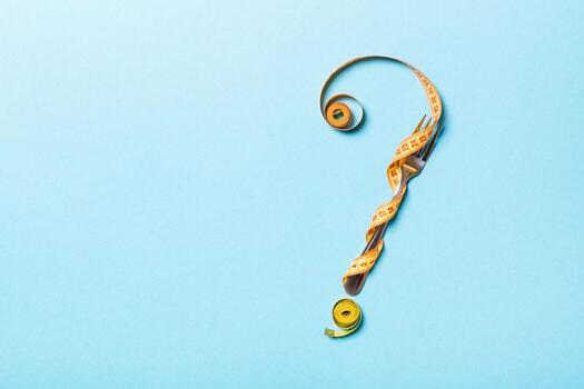 Top view of fork and measure tape in form of question mark on blue background. Overeating concept and copy space photo