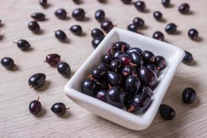 black currant in glassware on white wooden table top view photo