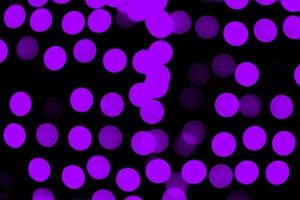 Unfocused abstract purple bokeh on black background. defocused and blurred many round light photo