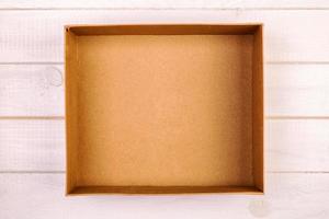 Opened brown blank cardboard box on wooden background, vintage, toned top view photo