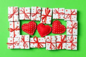 composición de cajas de regalo blancas navideñas y corazones textiles rojos sobre fondo colorido. concepto del día de san valentín foto