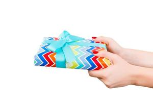 Woman hands give wrapped Christmas or other holiday handmade present in colored paper with blue ribbon. Isolated on white background, top view. thanksgiving Gift box concept photo