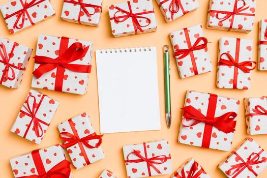 Holiday composition of notebook and gift boxes with red hearts on colorful background with empty space for your design. Top view of Valentine's Day concept photo