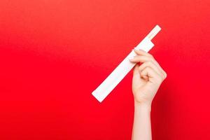 Woman's hand holding chopsticks in a pack on red background. Chinese food concept with empty space for your design photo