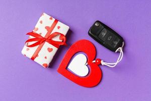 Top view of gift box, car key and wooden heart on colorful background. Luxury present for Valentine's day photo