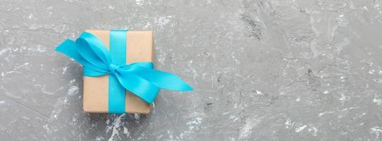Gift box with blue ribbon on gray background. Top view banner with copy space for you design. holidays concept