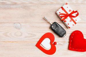 Top view of car key, gift box and heart as a present for Valentine's day on wooden background. Romance concept with copy space photo