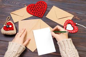 kraft paper envelope with wooden red heart on wooden table with copy space photo