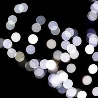 Unfocused abstract white bokeh on black background. defocused and blurred many round light photo