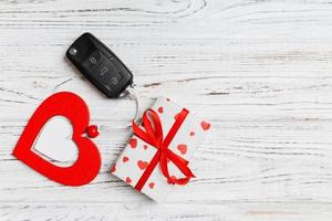 Top view of car key, gift box and heart as a present for Valentine's day on wooden background. Romance concept with copy space photo