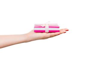 Woman hands give wrapped Christmas or other holiday handmade present in pink paper with white ribbon. Isolated on white background, top view. thanksgiving Gift box concept photo