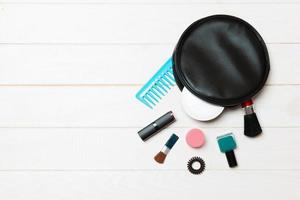 Aerial view of a leather cosmetics bag with make up beauty products spilling out on wooden background. Beautiful skin concept with copy space photo