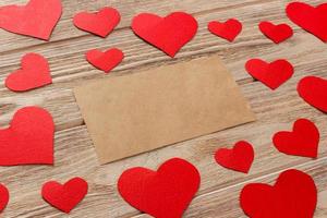 Valentines day background. Red hearts and empty letter on wooden background. Flat lay composition with copy space photo