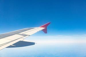 Aircraft wing on the clouds, flies on the city background photo