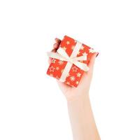 Woman hands give wrapped Christmas or other holiday handmade present in red paper with Gold ribbon. Isolated on white background, top view. thanksgiving Gift box concept photo