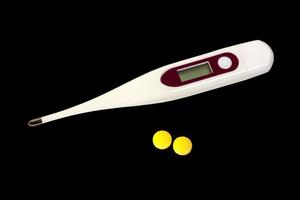 Modern medical thermometer with pills isolated on dark background photo