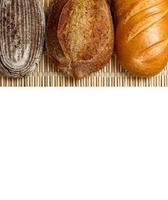 Different fresh bread on wooden plank, isolated on white background photo