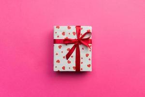 Background with gift box and hearts on pink Background. Top view with copy space for text photo