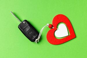 Top view of car key and wooden heart on colorful background. Luxury present for Valentine's day photo