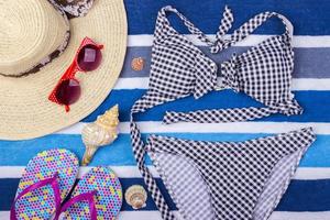 swimsuit with beach accessories on blue background. Sun Glasses Top View Seashell Shorts Flip flops Swimsuit photo