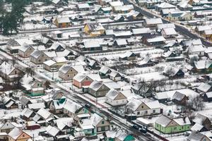 aerial panoramic winter view of village with houses, barns and gravel road with snow photo