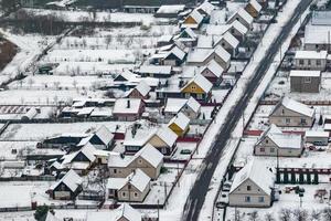 aerial panoramic winter view of village with houses, barns and gravel road with snow photo