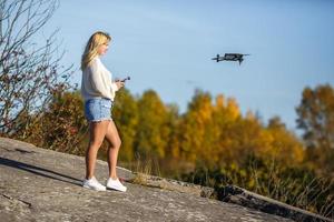 girl controls a drone staing on high rock in the mountains photo