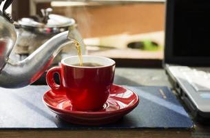 A red coffee cup is placed on the desk. office or at home with a notebook computer keyboard tablet pc photo