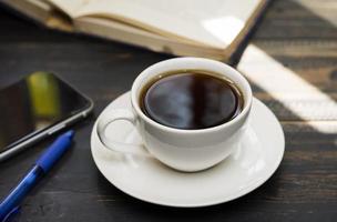 A white coffee cup is placed on the desk. office or at home with a notebook computer keyboard tablet pc photo