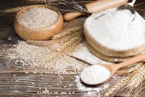 Organic Natural Whole Grain Flour in a Wooden Spoon and wheat seeds Ears of wheat on an old wooden floor photo