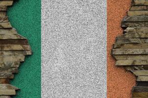 Ireland flag depicted in paint colors on old stone wall closeup. Textured banner on rock wall background photo