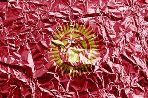 Kyrgyzstan flag depicted in paint colors on shiny crumpled aluminium foil closeup. Textured banner on rough background photo