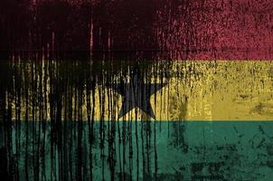 Ghana flag depicted in paint colors on old and dirty oil barrel wall closeup. Textured banner on rough background photo