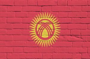 Kyrgyzstan flag depicted in paint colors on old brick wall. Textured banner on big brick wall masonry background photo