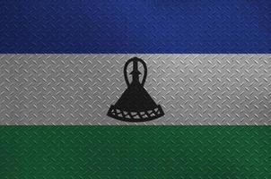Lesotho flag depicted in paint colors on old brushed metal plate or wall closeup. Textured banner on rough background photo