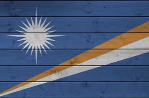 Marshall Islands flag depicted in bright paint colors on old wooden wall. Textured banner on rough background photo