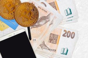 200 Czech korun bills and golden bitcoins with smartphone and credit cards. Cryptocurrency investment concept. Crypto mining or trading photo
