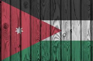Jordan flag depicted in bright paint colors on old wooden wall. Textured banner on rough background photo