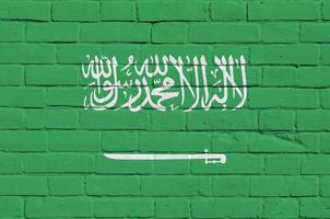 bandera de arabia saudita representada en colores de pintura en la pared de ladrillo antiguo. banner texturizado sobre fondo de mampostería de pared de ladrillo grande foto