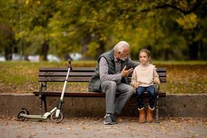 abuelo pasando tiempo con su nieta en un banco en el parque el día de otoño foto