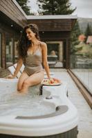 Young woman enjoying in outdoor hot tub on vacation photo