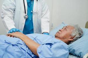 médico tomados de la mano paciente anciana asiática, ayuda y atención en el hospital. foto