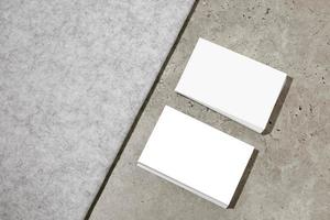 Blank white business cards on rough concrete surface. Mockup for branding identity. Two stacks, to show both sides of card. Template for graphic designers. Free space, copy space. photo