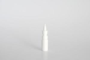 White plastic nasal spray bottle on white background. Nasal spray container, saline water solution for nose congestion treatment. Runny nose, colds. Free space, copy space. photo