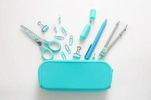 Blue stationery items on the white background. Creative, colorful background with school supplies. Flatlay, top view. Marker, pen, paper clips, scissors. photo