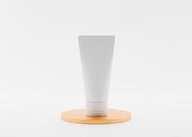 White and blank, unbranded cosmetic cream tube standing on golden podium. Skin care product presentation on white background. Elegant mockup. Skincare, beauty and spa. 3D rendering. photo