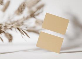 Blank brown cardboard business cards on white background with dried plants. Mock up for branding identity. Two cards, to show both sides. Template for graphic designers. Free, copy space. 3D rendering photo