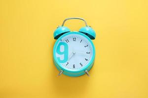 Blue alarm clock on the yellow background. Morning, time to wake up. Free space, copy space. photo