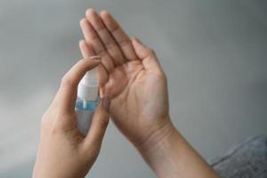 Close up of asian woman use alcohol spray for hand hygiene, bacteria and virus protection concept. photo