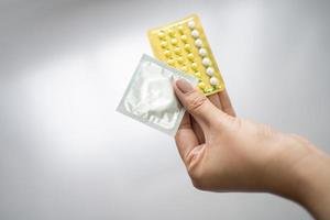 Woman holding contraceptive pills and condoms in hand, protection against pregnancy or sexually transmitted diseases photo